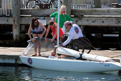 A sailor and a volunteer work to roll 2.4mR sails on the dock at The Clagett Regatta in Newport