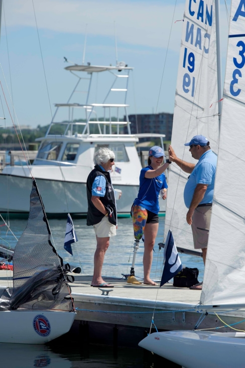A photo of Siobhan MacDonald high-fiving a Clagett volunteer on the dock at Clagett Newport