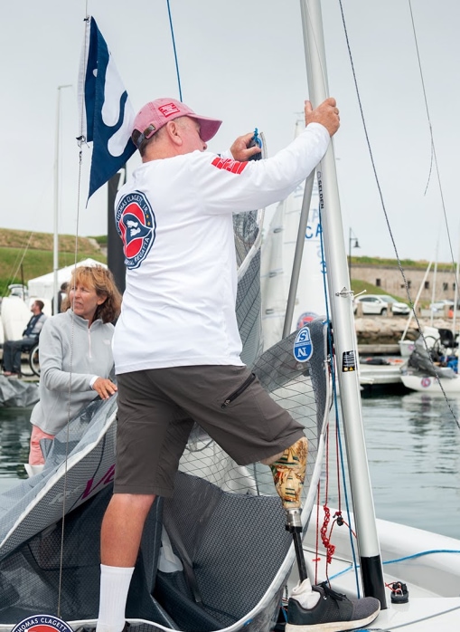 A Clagett sailor feeds the mainsail of an RS Venture Connect into the mast at Clagett Newport